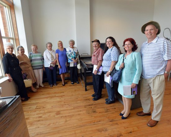 Full circle: Former Anderson-Newcomb/Stone and Thomas employees tour world-class Visual Arts Center Fern Fitzpatrick, Lottie Woody, Elsie Singleton, Lula Cremeans; Donna Rawley; Opal Blake; Yvonne and Virgil Newman; and Jerry and Shirley Blake, the former Anderson-Newcomb employees who toured the building, stand with an early 1900s printing press.