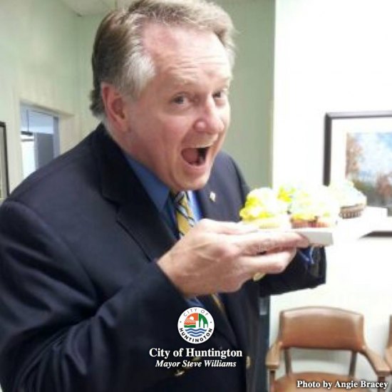 Mayor Williams eating gold and blue cup cakes.